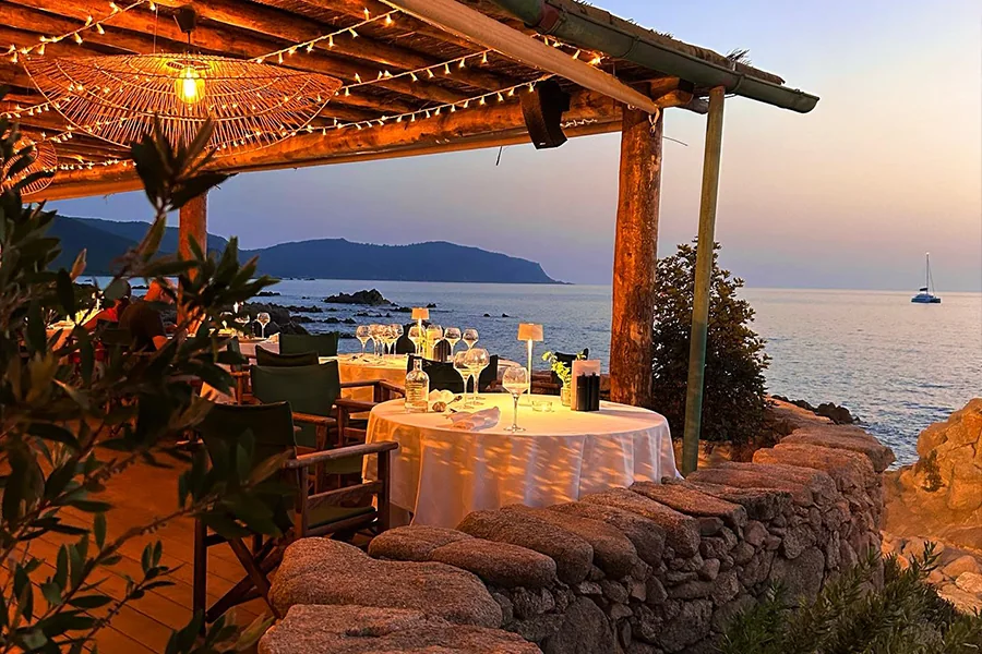 Table dressée en bord de mer à la Réserve de Saparella au coucher du soleil